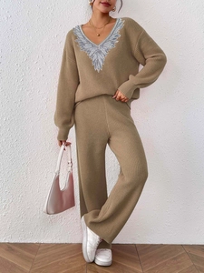 Detailed close-up of V-neck knit sweater with silver sequin wing embroidery and matching pants