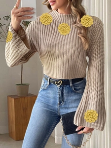 Detail of flared sleeves with yellow crochet floral patches on a beige knit sweater