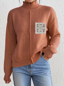 Close-up of brick red knit sweater featuring delicate white floral lace pocket detail
