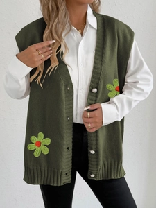 Gilet en tricot vert foncé avec broderies florales et boutons nacrés sur chemise