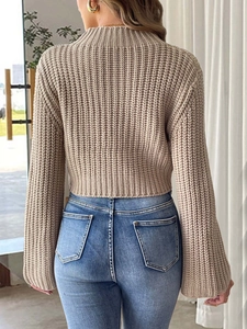 Macro detail of beige chunky knit texture and bell sleeves on a cropped sweater