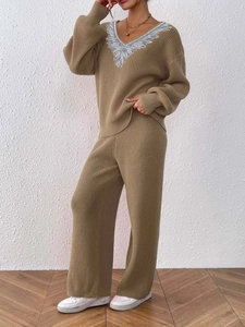 Detail of V-neck knit sweater with silver wing embroidery and wide-leg ribbed trousers
