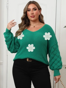 Detail of green V-neck knit sweater featuring 3D white floral applique and scale texture sleeves