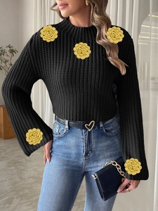Detail of hand-crocheted yellow floral patches on a black knit sweater with rib texture