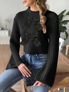 Close-up of black chunky knit sweater featuring ribbon bows and elegant flare sleeves