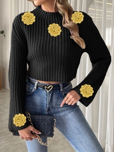 Detail of yellow handmade crochet roses on a black long sleeve cropped knit sweater
