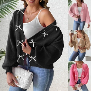 Detail of knitted cardigan showing white ribbon bows and heavy gauge texture