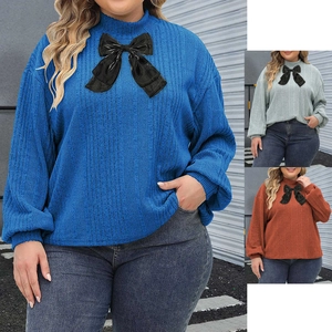 Close-up of ribbed knit texture and decorative glossy bow on a mock neck top