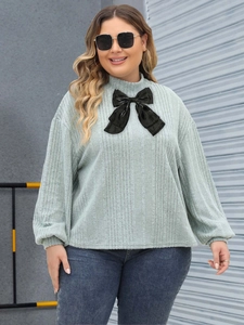 Sage green plus size rib-knit top with a large black bow and lantern sleeves