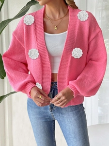 Detailed close-up of pink knitted cardigan featuring white 3D floral applique accents