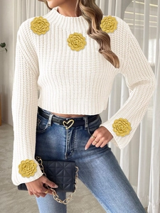 Detail of white turtleneck knit sweater with yellow crochet floral appliques and flared sleeves