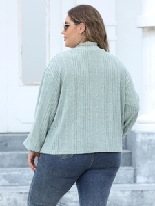 Detailed texture of green ribbed knit fabric on a long sleeve mock neck plus size top