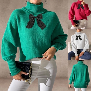 Detail of knit sweater with large black bow on chest and ribbed cuffs in multiple colors