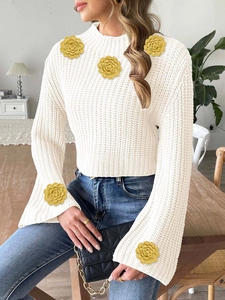 Detail of white waffle knit sweater with yellow crochet flower patchwork on flare sleeves