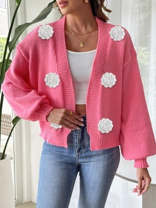 Detailed close-up of pink knit cardigan with white 3D crochet flower decorations