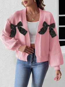 Pink knit cardigan with large black satin bows and contrasting button details