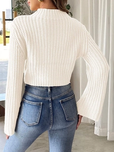 Close-up of white crochet patchwork knit top with bell sleeves and blue denim jeans