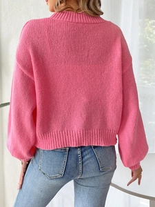 Close-up back view of bright pink chunky knit sweater with ribbed cuffs and loose fit