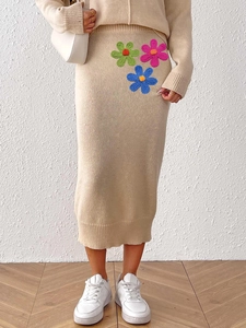 Close-up of beige knit midi skirt featuring colorful handmade crochet flower appliques
