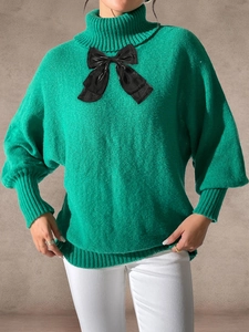 Detailed view of emerald green high neck sweater with a large decorative black bow