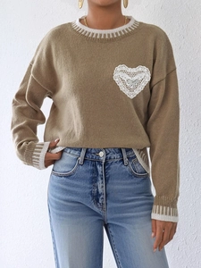 Detail of the white lace heart applique and silver bow on the khaki knit sweater
