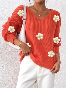 Close-up of V-neck coral orange sweater with 3D white knitted floral details and texture