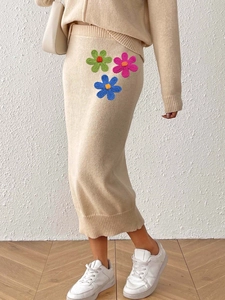 Detailed close-up of beige knitted midi skirt featuring colorful crochet floral appliques