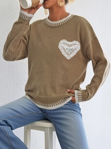 Detail of camel knit sweater featuring white lace heart appliqué and bow decoration