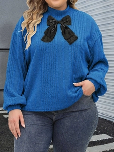 Close-up of royal blue ribbed knit top featuring a large black bow tie neckline