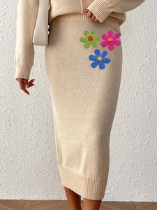 Detail of beige knit midi skirt featuring colorful handcrafted floral embroidery patterns