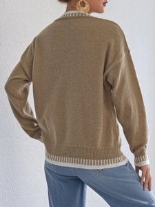 Detail of khaki knit sweater showing white contrast stripes on ribbed cuffs and hemline