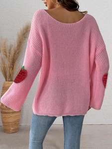 Close-up of pink knit sweater showing 3D strawberry patches on flared sleeves