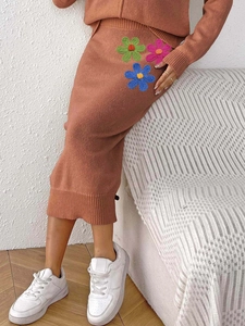 Detail of brown knit skirt featuring colorful crochet flower embroidery and textured fabric