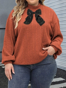 Plus size rust red ribbed mock neck long sleeve top with a black bow accent detail