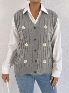 Detail of cable knit vest featuring floral 3D daisy appliques and front buttons