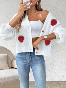 Dettaglio del cardigan in maglia bianca con applicazioni di fragole 3D fatte a mano
