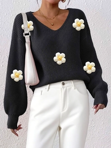 Detailed macro view of 3D hand-crocheted white flowers on a black V-neck sweater