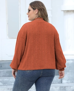 Detail view of the orange plus-size ribbed knit top with a high neckline and soft texture