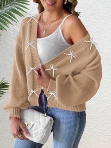 Detail of khaki knit cardigan featuring elegant white ribbon bows and ribbed cuffs