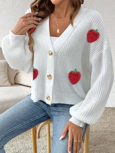 Dettaglio ravvicinato del cardigan bianco in maglia grossa con fragole 3D applicate
