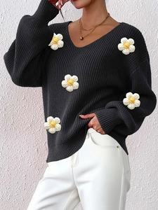 Detailed close-up of 3D knit floral applique and V-neckline texture on black sweater
