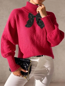 Close-up of rose red turtleneck sweater with lantern sleeves and black bow detail