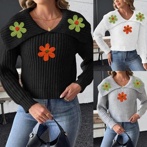 Detailed close-up of knit sweater featuring floral crochet appliques and a wide collar design