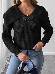 Détail du col en V avec grand nœud noir sur un pull court en maille épaisse pour femme