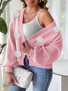 Close-up of pink knit cardigan with white 3D crochet roses and ribbed cuffs