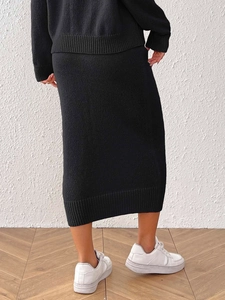 Detail view of the black knit two-piece set showing texture and ribbed hem on the midi skirt