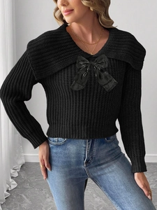 Détail d'un pull en maille noire pour femme orné d'un grand nœud élégant sur le col