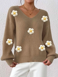 Detailed macro view of 3D crochet flower patches and texture on a camel knit sweater