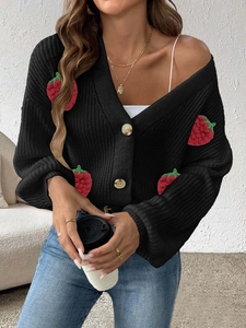 Dettaglio cardigan in maglia nera con decorazioni di fragole 3D e scollo a V profondo