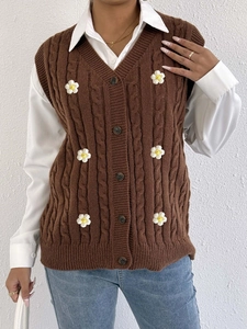 Close-up of cable knit cardigan vest featuring delicate white daisy flower appliques